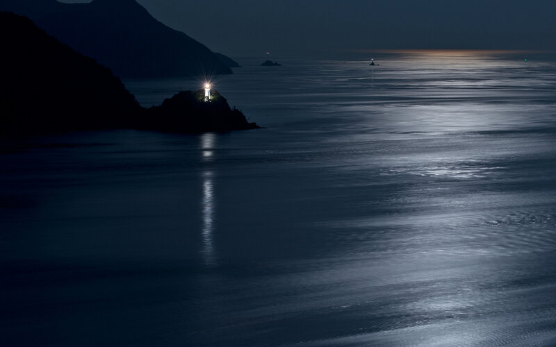 Lighthouse on Rocky Shore — Blue, Serene, Night, Photograph, Ocean, Mountain