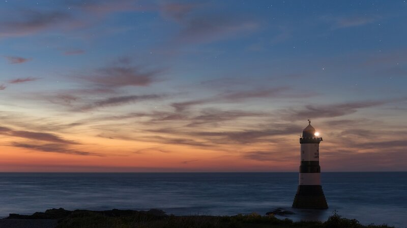 Lighthouse on Rocky Shore — Blue, Serene, Night, Photograph, Ocean, Sky