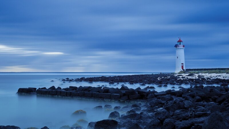 Lighthouse on Rocky Shore — Blue, Serene, Night, Photograph, Rocks, Sea, Sky