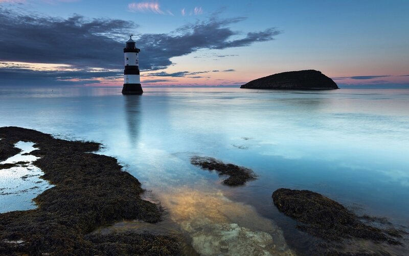 Lighthouse on Rocky Shore — Blue, Serene, Sunset, Photograph, Island