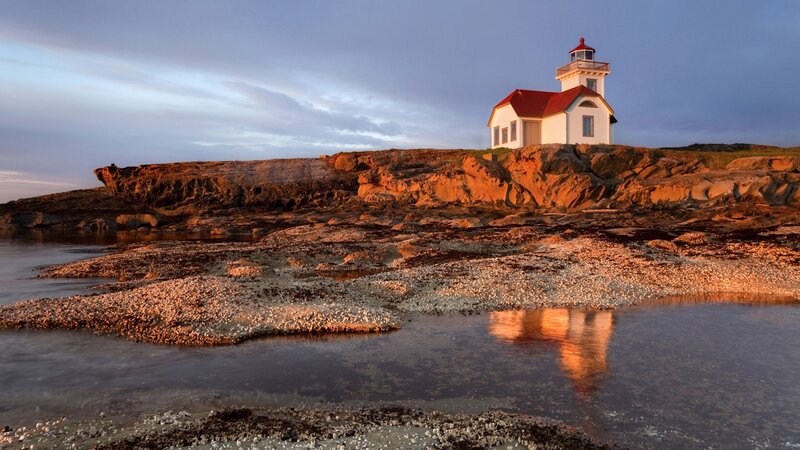 Lighthouse on Rocky Shore — Blue, Serene, Sunset, Photograph, Rocks, Water, Sky