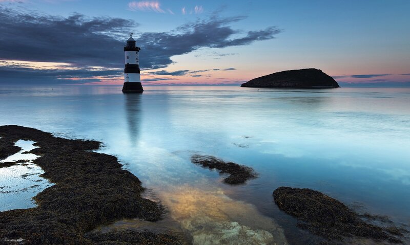Lighthouse on Rocky Shore — Blue, Serene, Sunset, Photograph, Sea, Island
