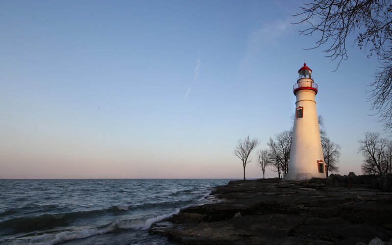 Lighthouse on Rocky Shore — Blue, Serene, Sunset, Photograph, Sea