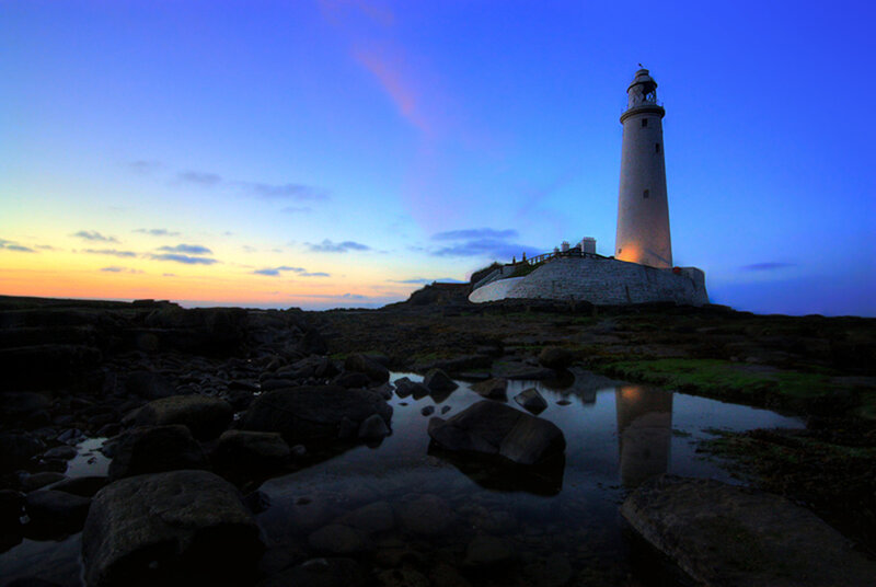 Lighthouse on Rocky Shore — Blue, Serene, Sunset, Photograph