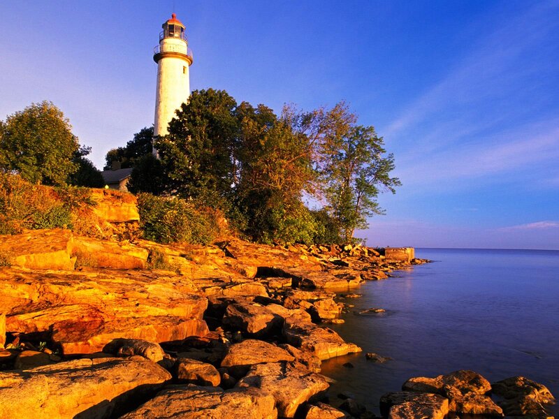 Lighthouse on Rocky Shore — Blue, Serene, Sunset, Photograph, Trees, Ocean, Sky