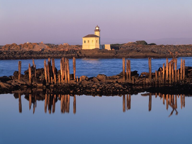 Lighthouse on Rocky Shore — Blue, Serene, Sunset, Photograph, Wooden Posts, Rocks