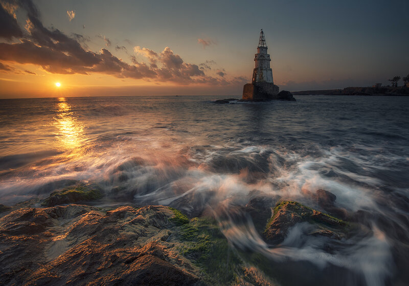 Lighthouse on Rocky Shore — Orange, Dramatic, Sunset, Photograph, Sun, Ocean