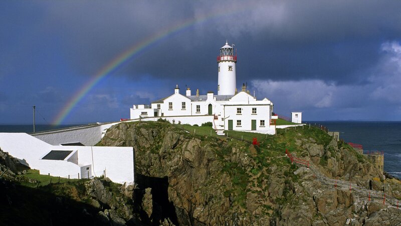 lighthouse with rainbow over sea