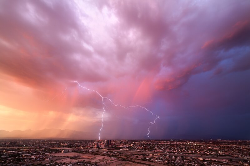 Lightning over city at sunset