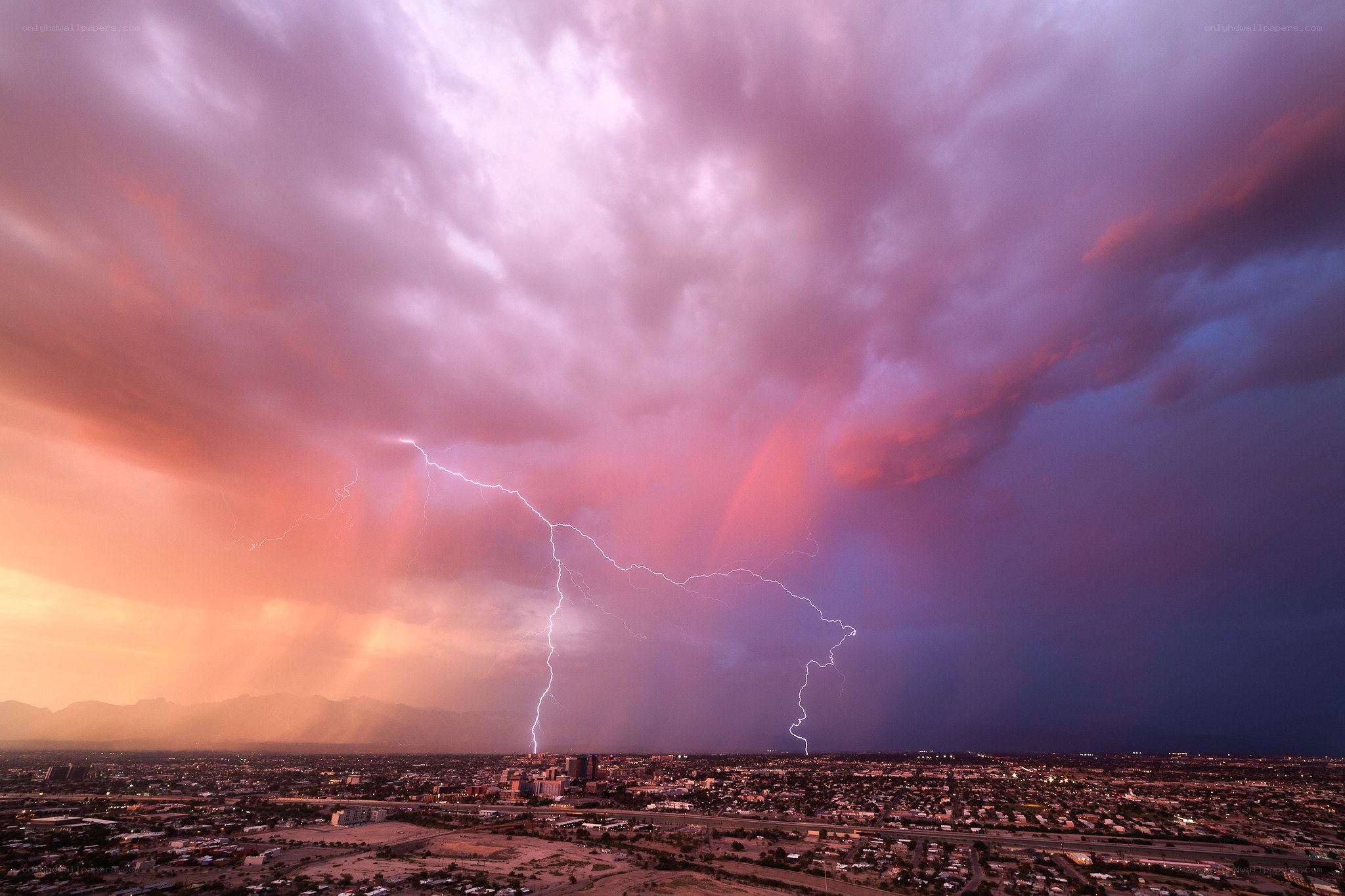 Lightning over city at sunset