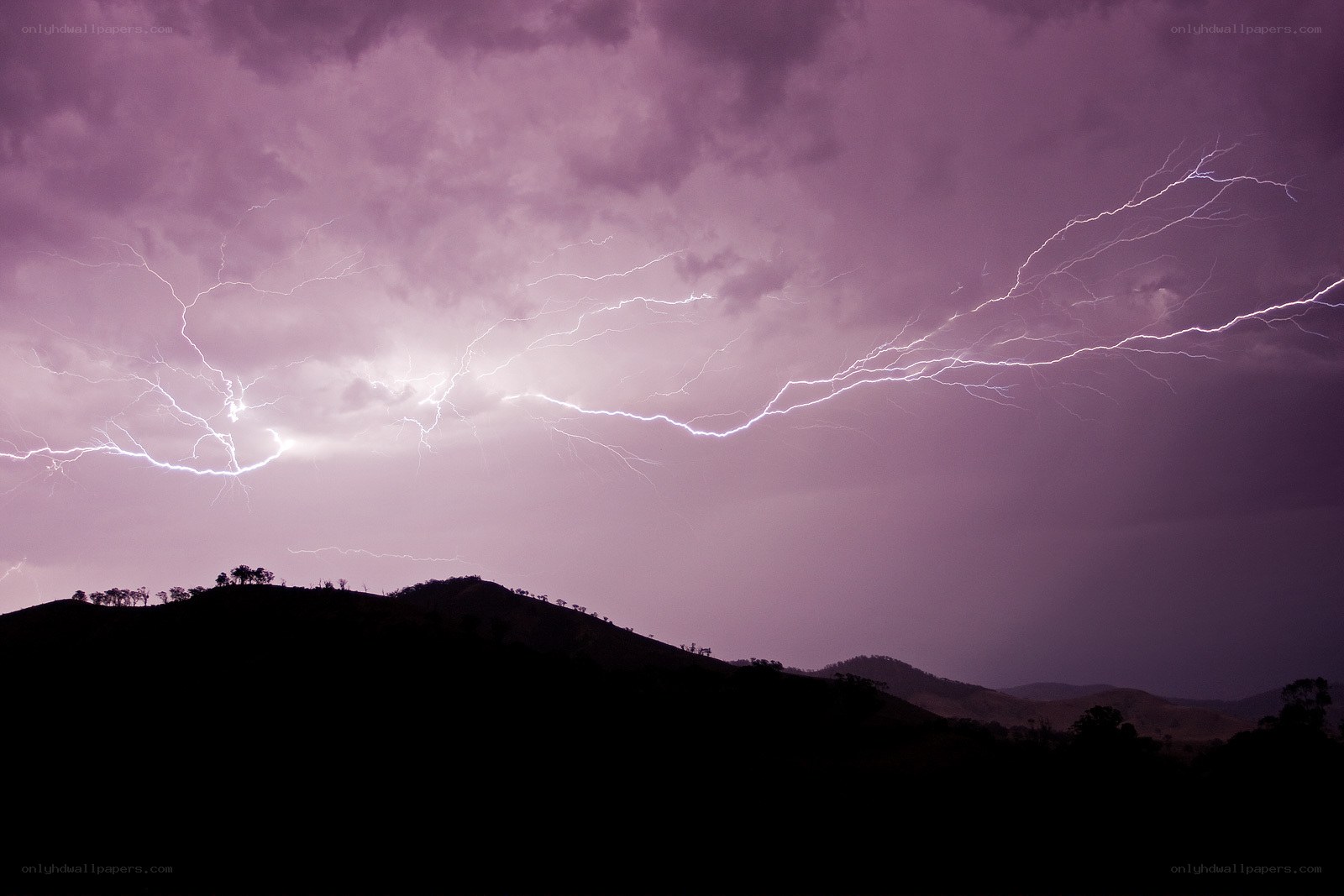Lightning over hills at dusk