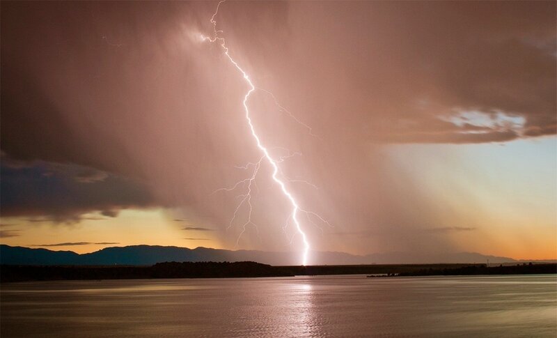 Lightning strike over lake at dusk