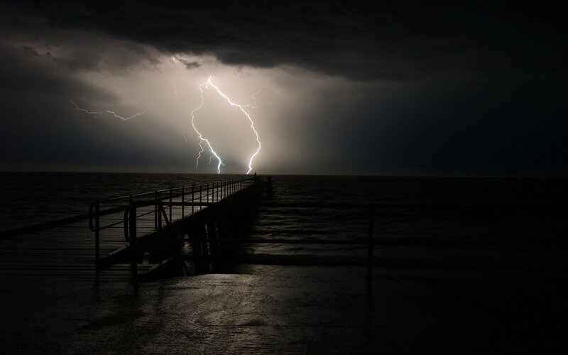 Lightning strikes over ocean pier