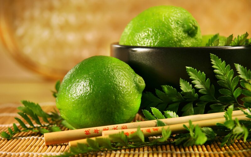 Limes with chopsticks on bamboo mat