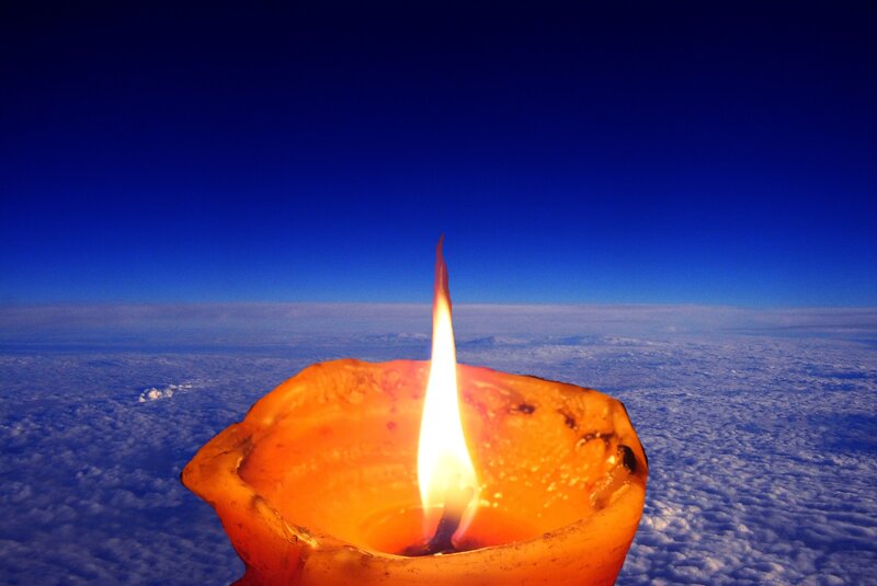 Lit Candle Above Clouds