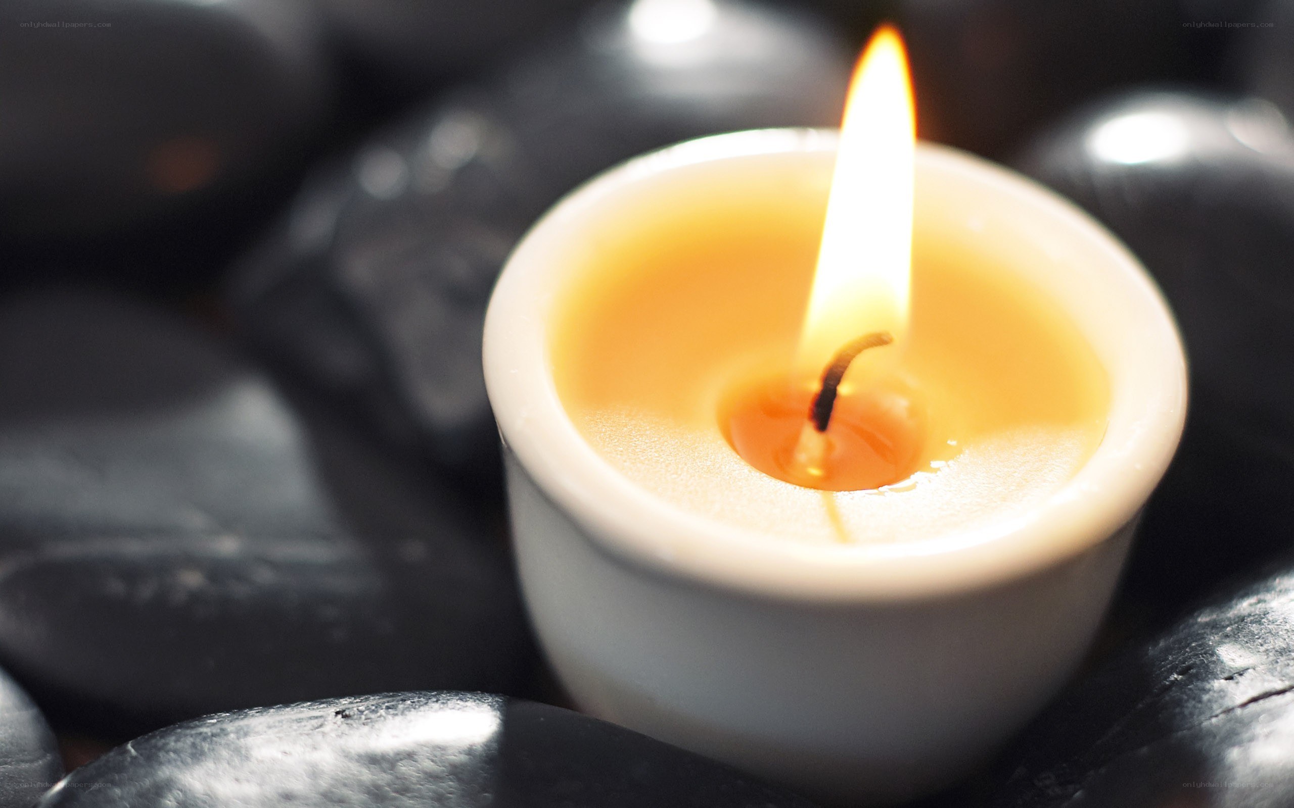 lit candle on black stones