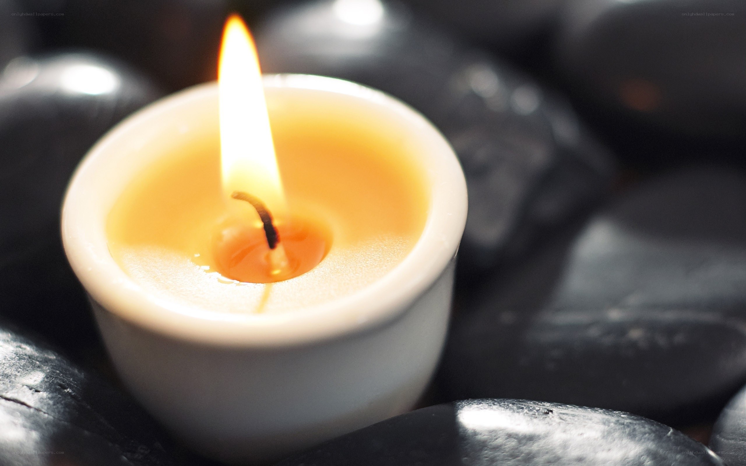 lit candle on black stones