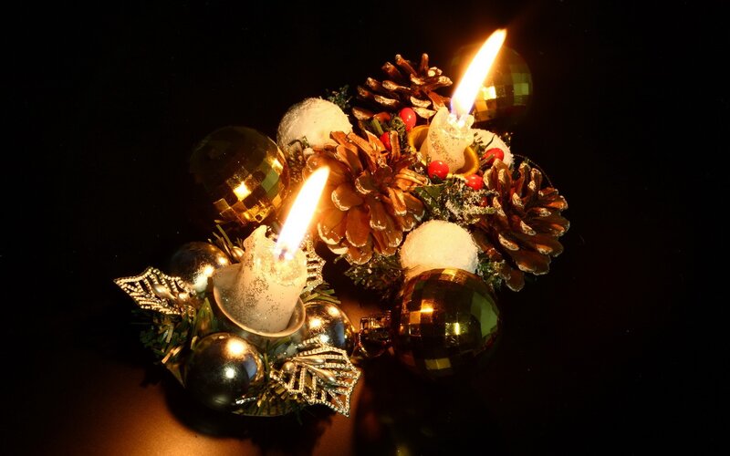 lit candles on holiday arrangement