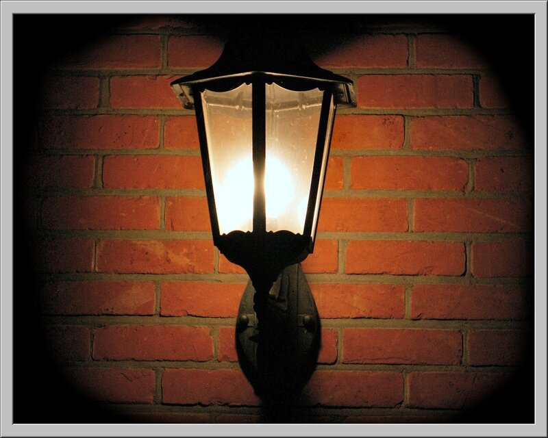 Lit Lantern on Brick Wall