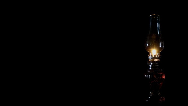 lit oil lamp in darkness