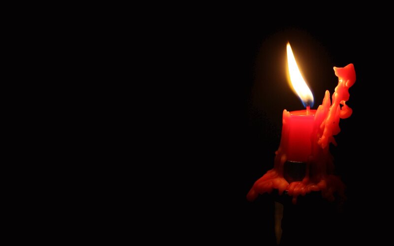 lit red candle in darkness