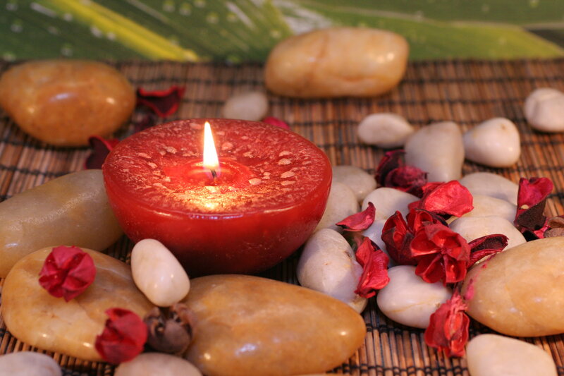 Lit Red Candle on Stones