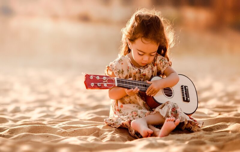 Little Girl Playing Ukulele — Brown