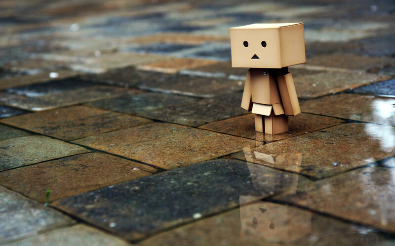 lonely cardboard figure on wet pavement