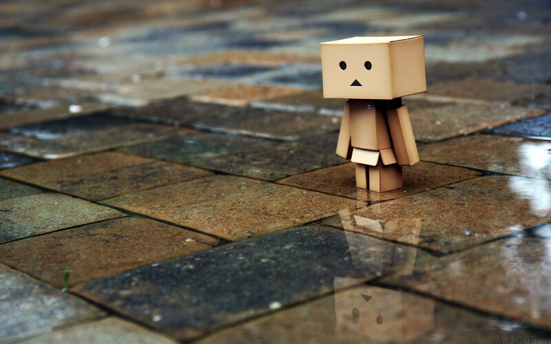lonely cardboard figure on wet pavement