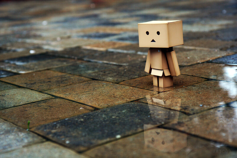 lonely cardboard figure on wet pavement