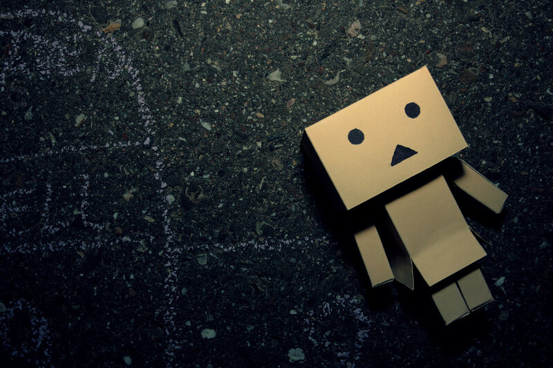 lonely cardboard robot on pavement