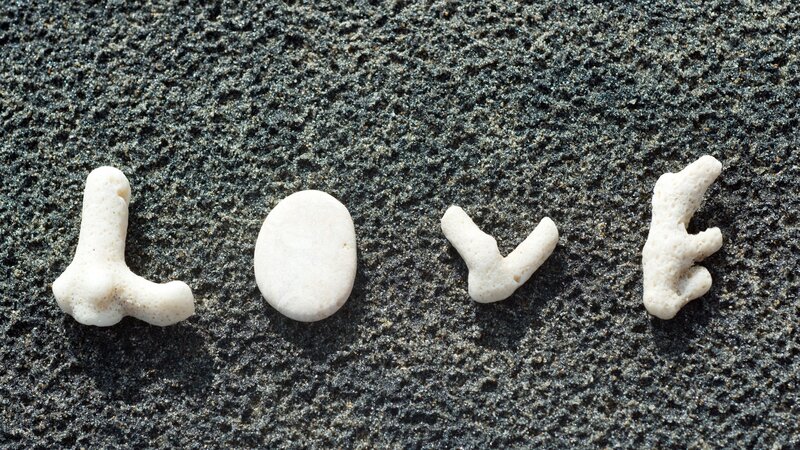 Love spelled with coral on sand