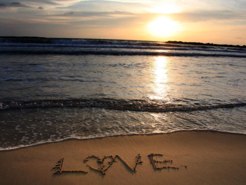 Love written in the sand at sunset