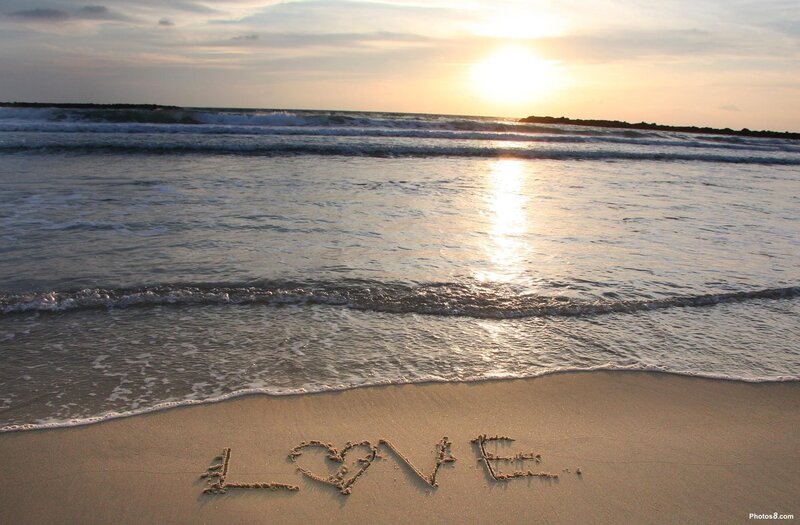Love written in the sand at sunset