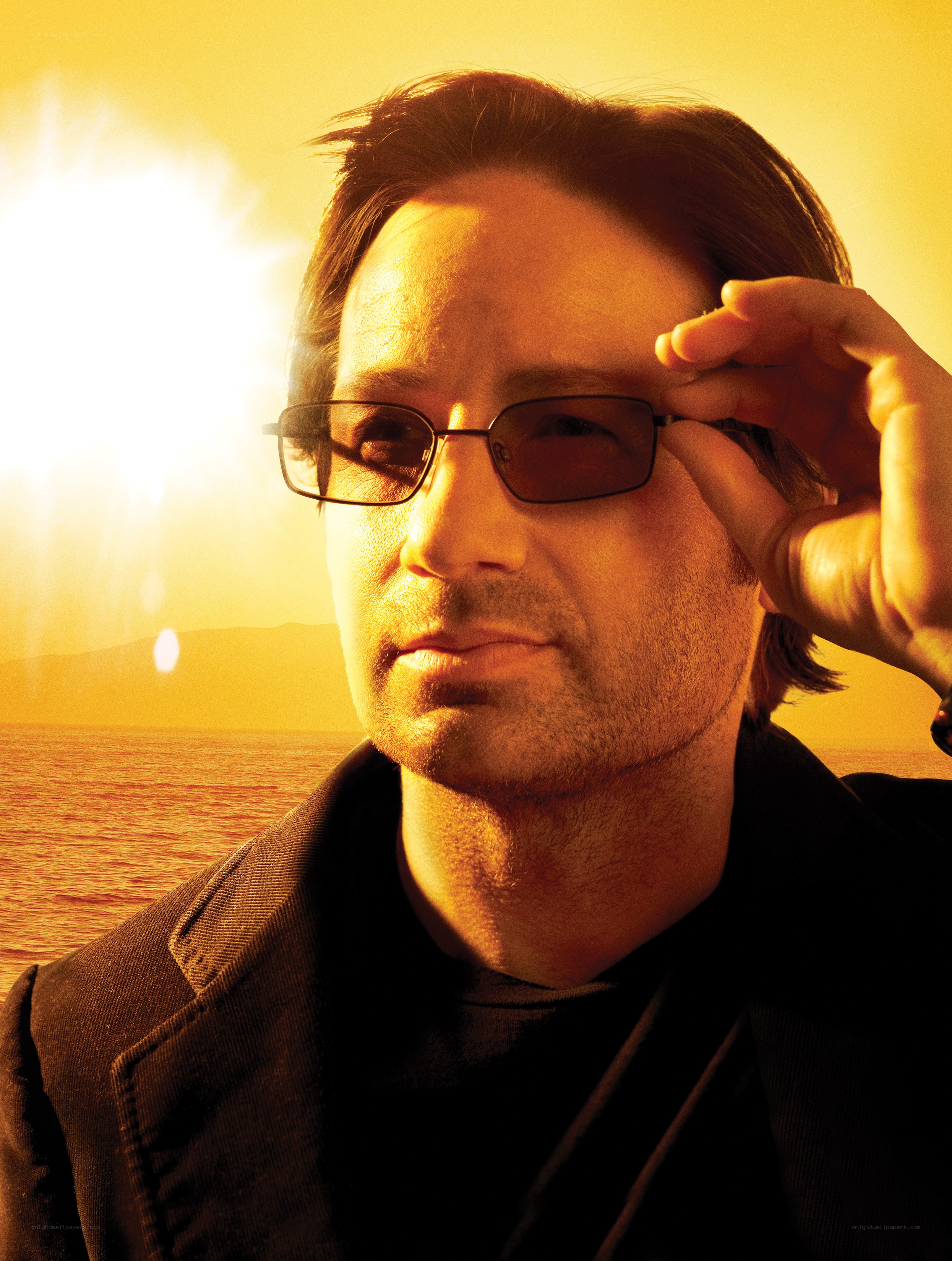 man adjusting glasses at sunset