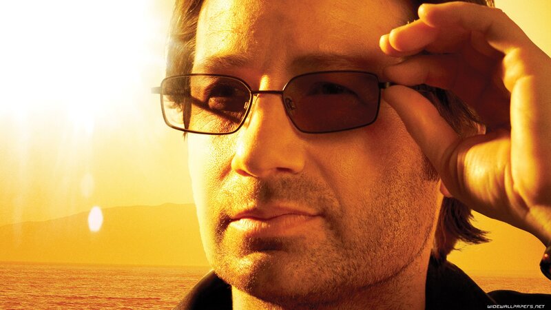 man adjusting sunglasses at sunset