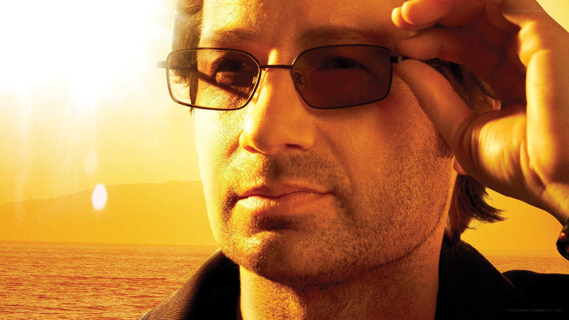 man adjusting sunglasses at sunset