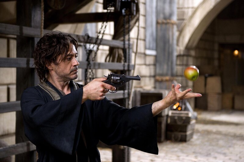 man aiming gun at apple