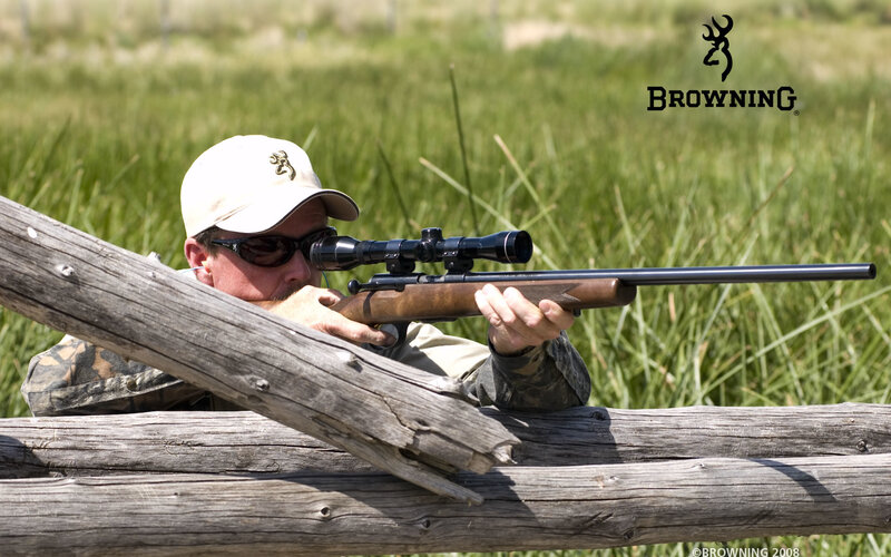 man aiming rifle from behind log