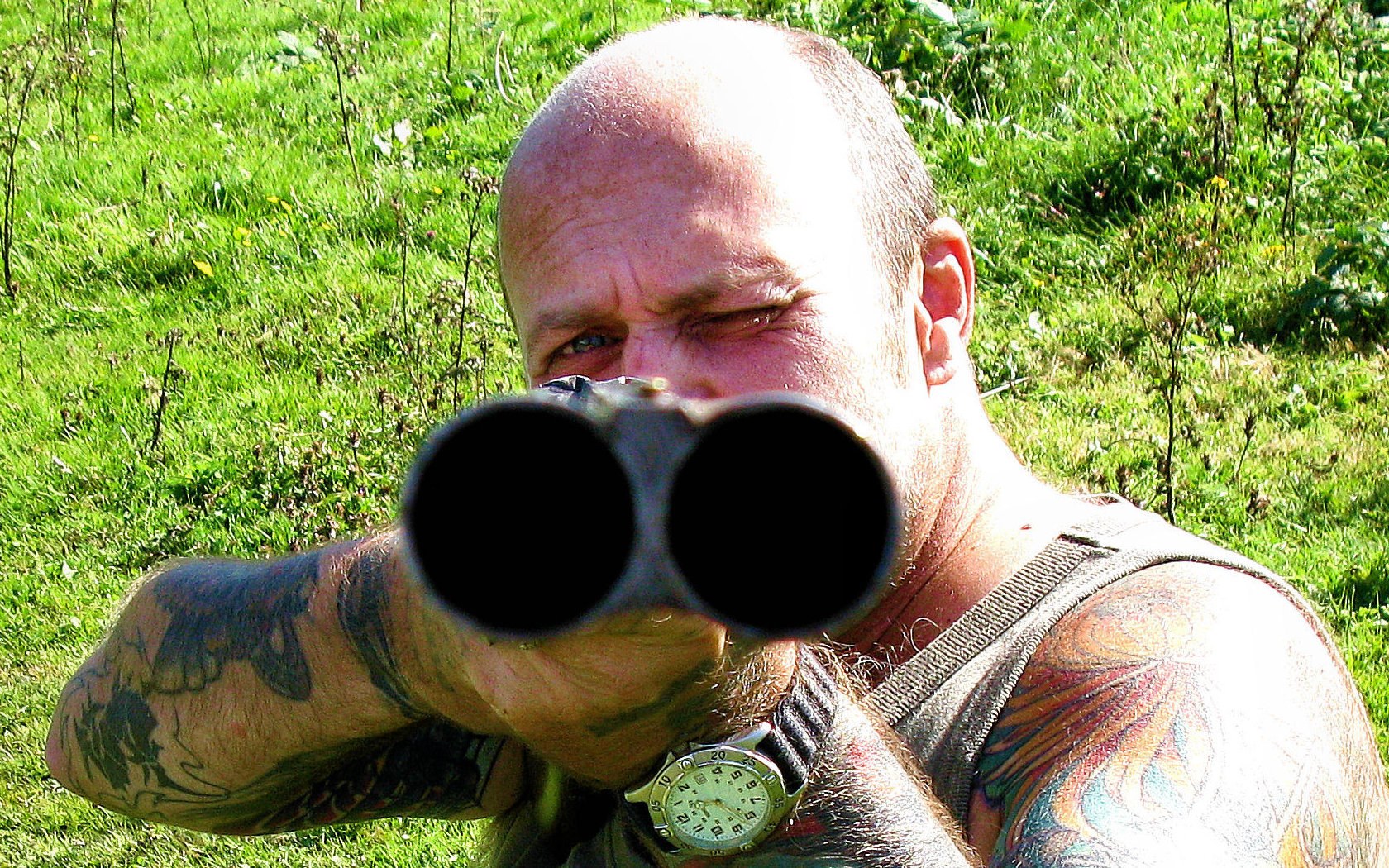man aiming shotgun outdoors