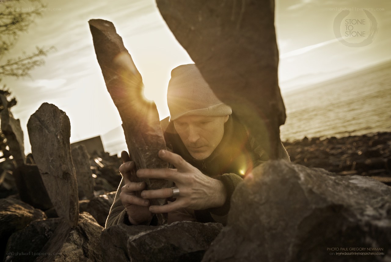 man arranging stones at sunset