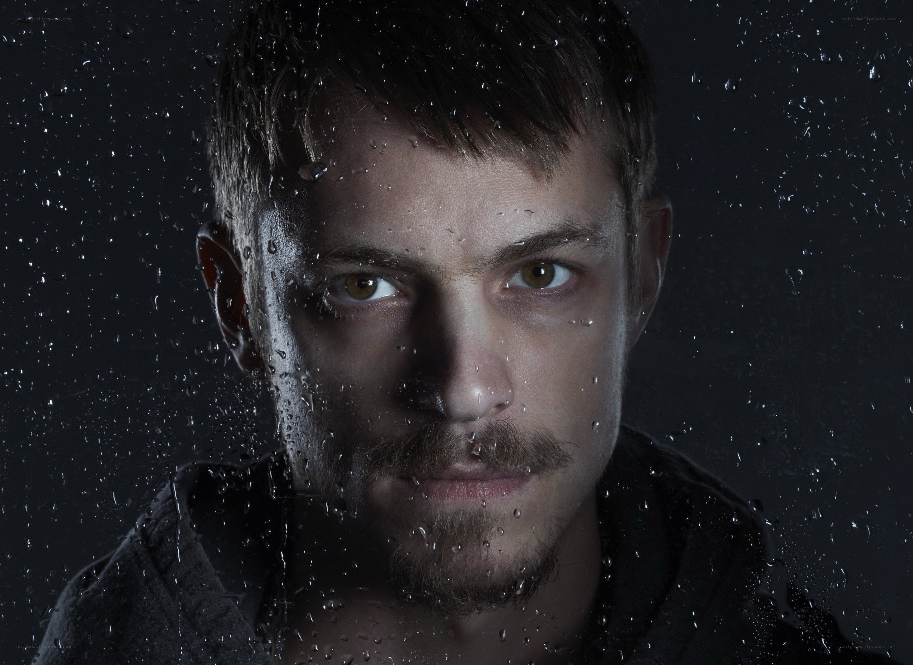 man behind rain-covered glass