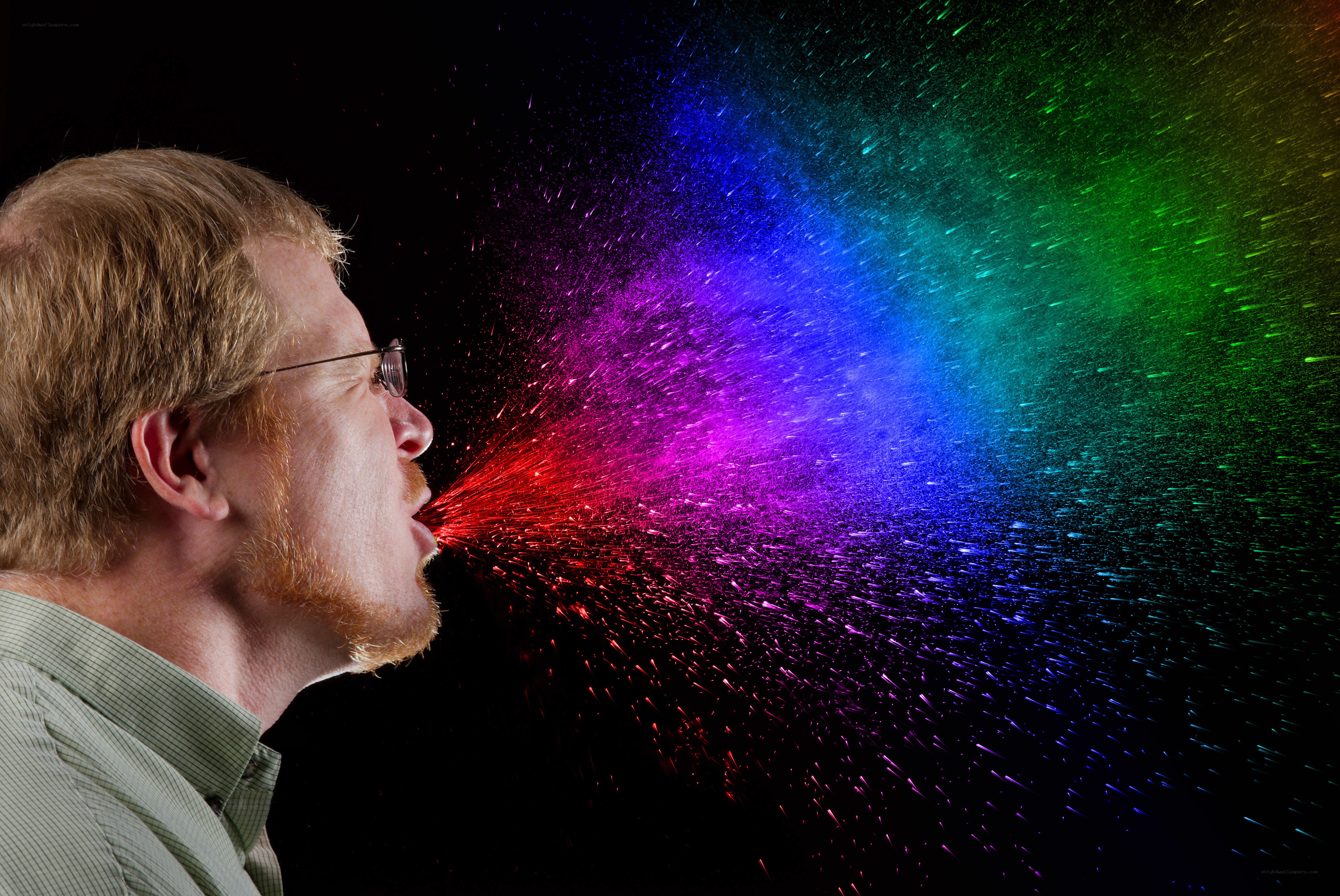 man blowing rainbow spray