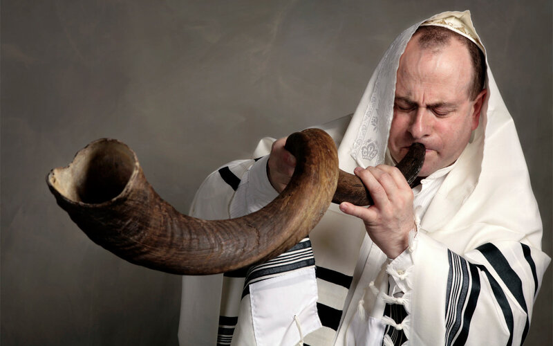 man blowing shofar in prayer