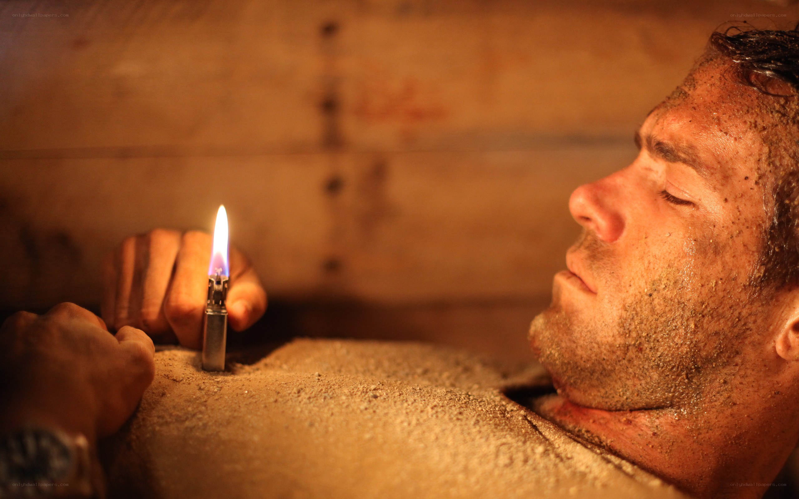man buried in sand with lighter