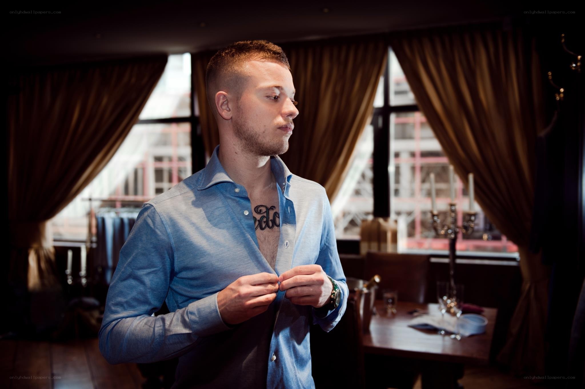 man buttoning blue shirt