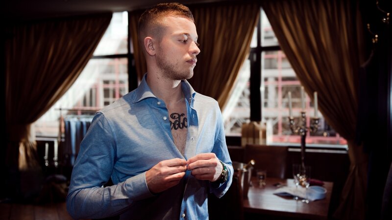 man buttoning blue shirt