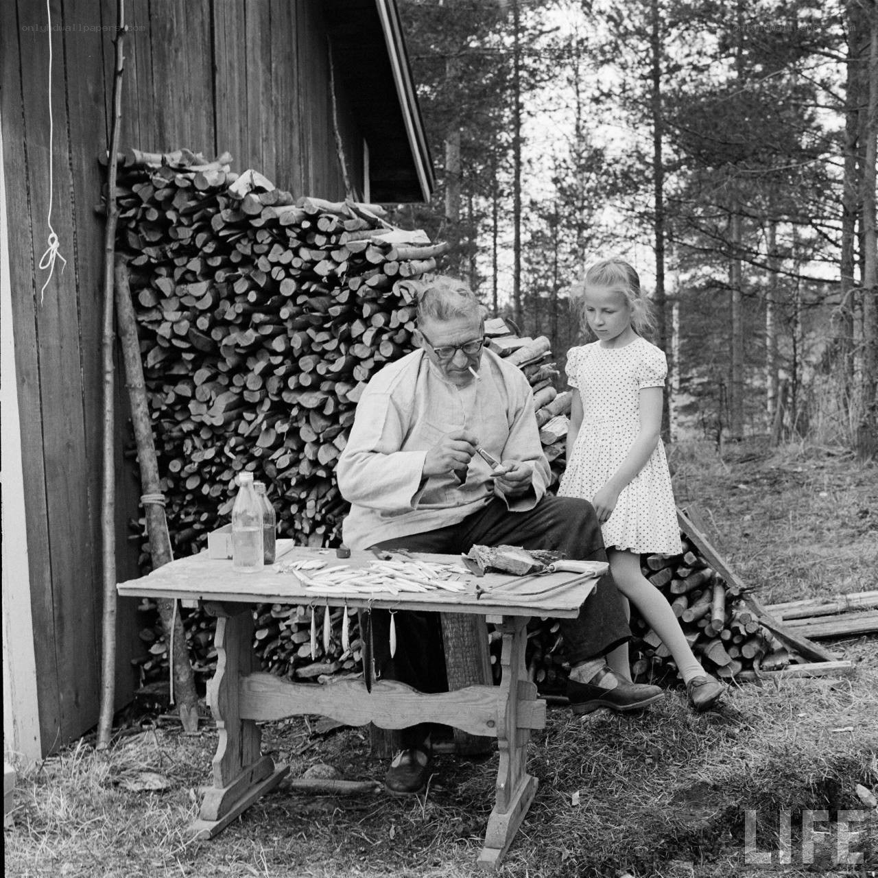 Man carving fishhooks with a girl