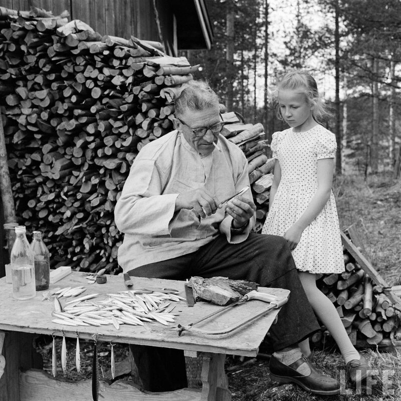 Man carving fishing lures with girl