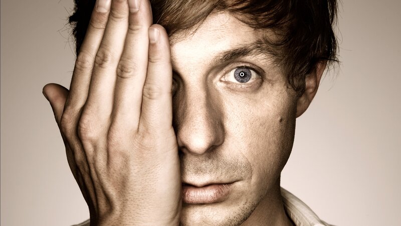man covering one eye with hand